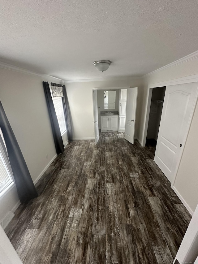 unfurnished living room with a textured ceiling, dark hardwood / wood-style floors, and ornamental molding