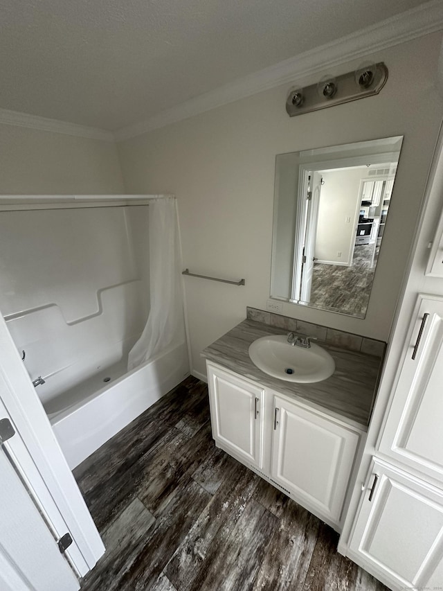 bathroom with crown molding, hardwood / wood-style floors, shower / bath combination with curtain, and vanity