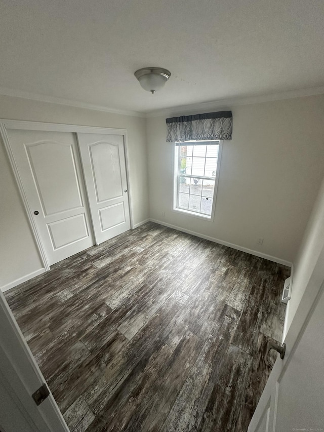 unfurnished bedroom with dark hardwood / wood-style floors, a closet, and ornamental molding