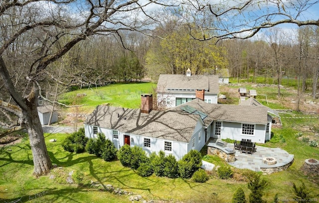 back of property featuring a fire pit, a patio area, and a lawn