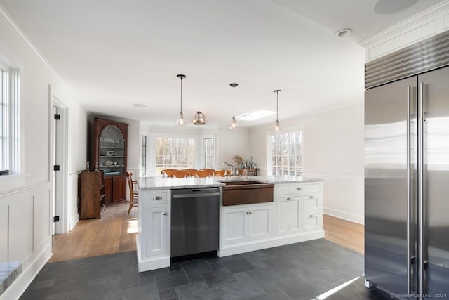 kitchen with a healthy amount of sunlight, white cabinetry, stainless steel appliances, and hanging light fixtures