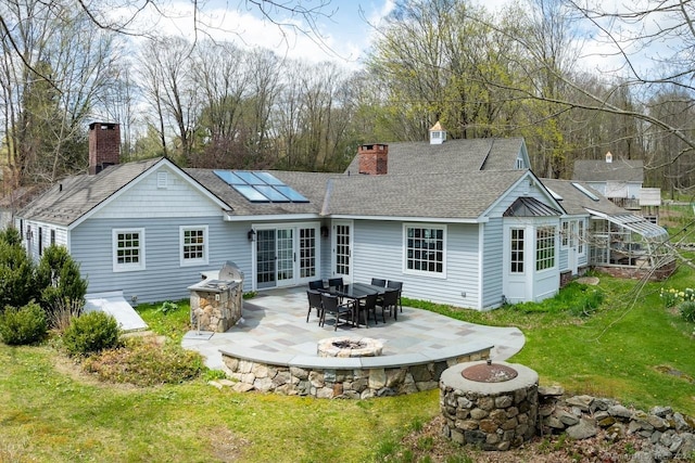 rear view of house with a fire pit, a patio area, a lawn, and french doors