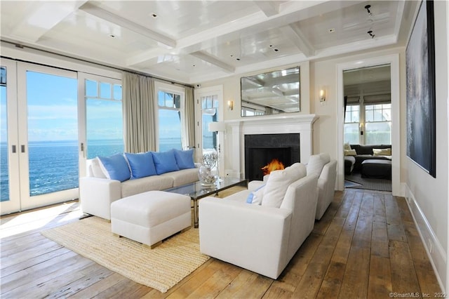 living room with a wealth of natural light, a water view, wood-type flooring, and coffered ceiling