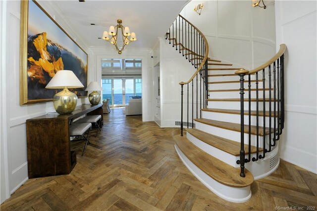 entrance foyer featuring a notable chandelier, dark parquet floors, and ornamental molding