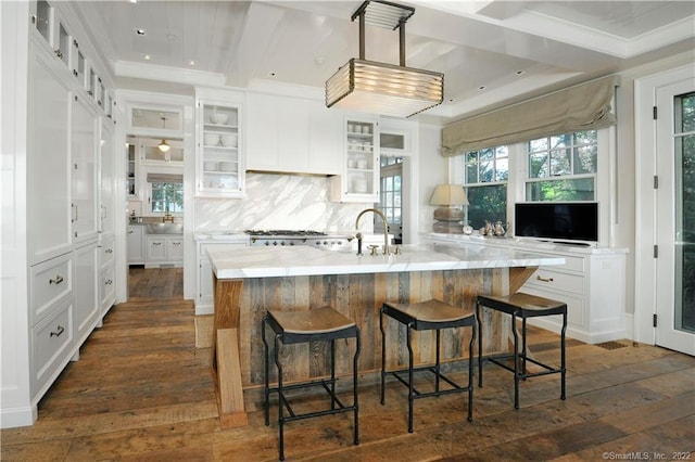 kitchen featuring a large island, dark hardwood / wood-style floors, a kitchen bar, decorative backsplash, and white cabinets