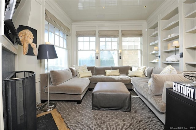 living room with hardwood / wood-style floors, built in shelves, and crown molding