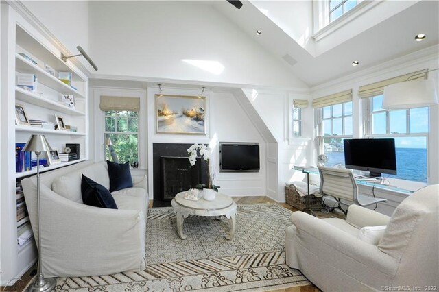 living room with built in shelves, light hardwood / wood-style floors, ornamental molding, and high vaulted ceiling