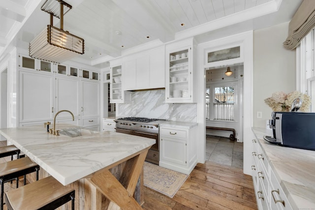 46 Compo Mill Cv, Westport, CT 06880 - kitchen featuring high end stove, a breakfast bar area, light wood-style floors, white cabinets, and light stone countertops