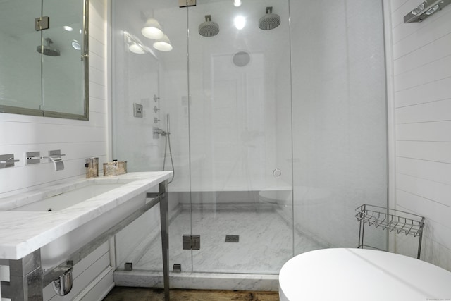 bathroom featuring sink, a shower with shower door, and wooden walls