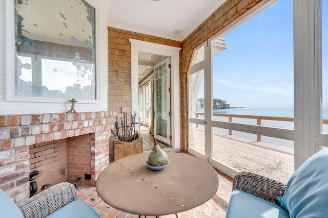 sunroom / solarium with an outdoor brick fireplace and a water view