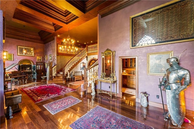 interior space featuring hardwood / wood-style floors, a chandelier, beamed ceiling, a high ceiling, and ornamental molding