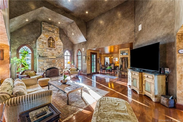 living room with high vaulted ceiling, wood-type flooring, and a stone fireplace