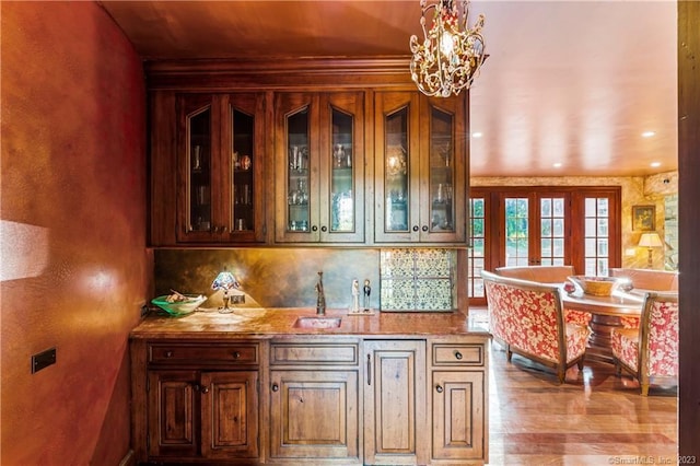 bar featuring pendant lighting, crown molding, backsplash, sink, and hardwood / wood-style flooring