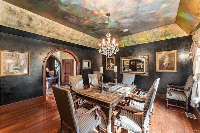 dining space featuring lofted ceiling, dark hardwood / wood-style floors, and an inviting chandelier