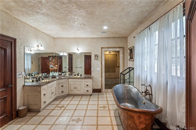 bathroom with vanity, a textured ceiling, a wealth of natural light, and tile patterned floors