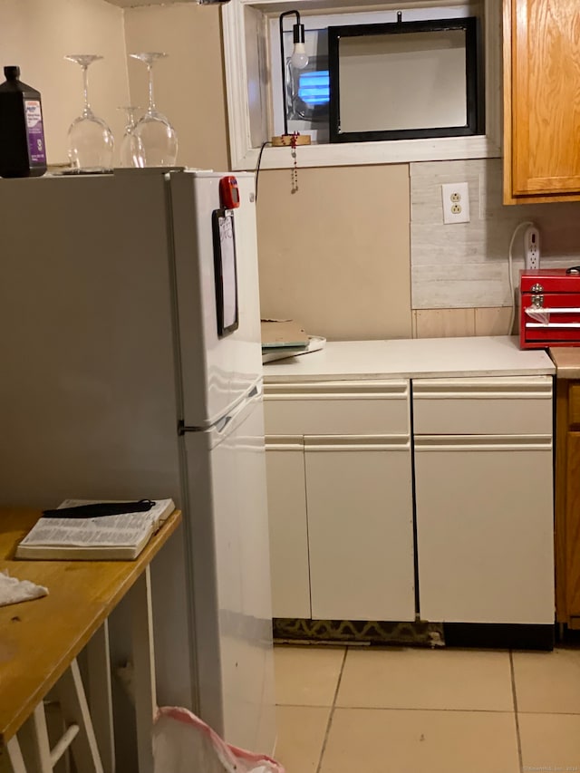 kitchen featuring light tile floors and white fridge