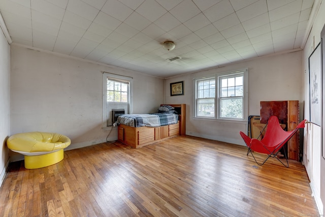 bedroom with ornamental molding and light hardwood / wood-style floors