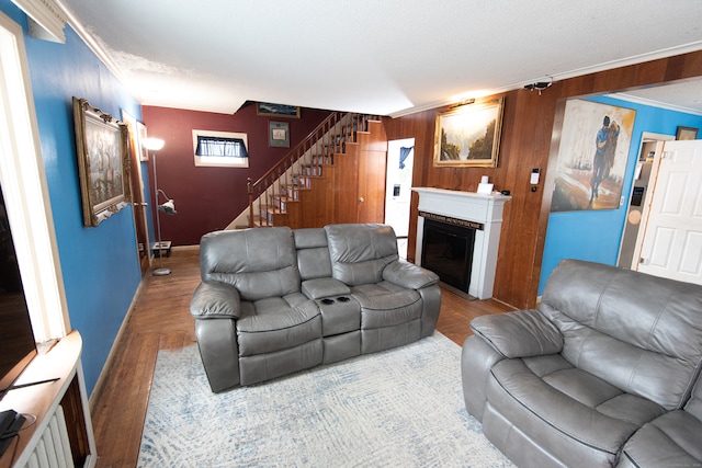 living room with crown molding, wood walls, and hardwood / wood-style flooring