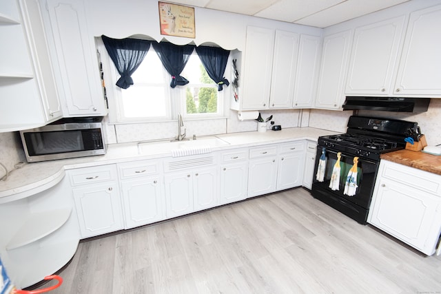 kitchen featuring black gas range oven, white cabinetry, backsplash, sink, and light hardwood / wood-style floors