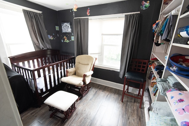 bedroom with dark hardwood / wood-style flooring and a crib