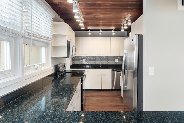 kitchen featuring white cabinets, appliances with stainless steel finishes, track lighting, and dark wood-type flooring