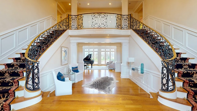 entryway with light hardwood / wood-style flooring, decorative columns, and a high ceiling