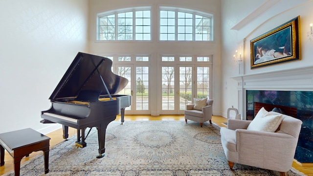 sitting room with a high ceiling, light wood-type flooring, a fireplace, and a wealth of natural light