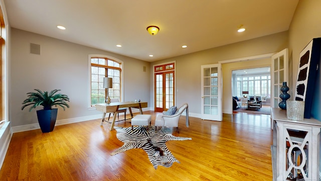 living area with plenty of natural light, french doors, and light hardwood / wood-style floors