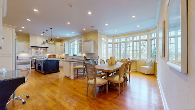 dining area featuring a healthy amount of sunlight, light hardwood / wood-style flooring, crown molding, and sink