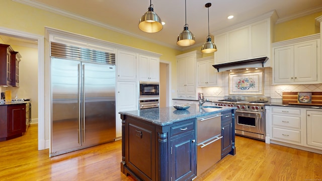 kitchen featuring built in appliances, tasteful backsplash, a kitchen island with sink, white cabinets, and light wood-type flooring