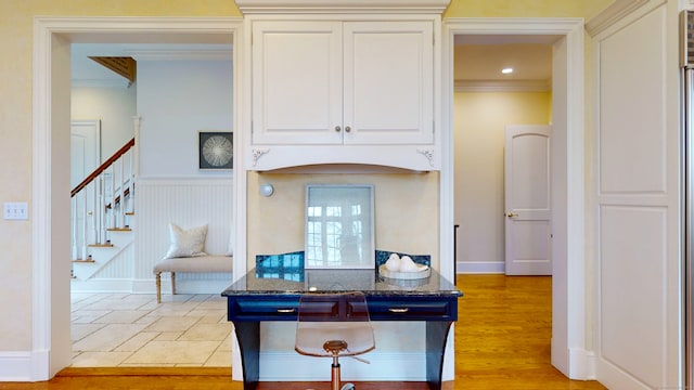 kitchen featuring crown molding, dark stone counters, light tile flooring, and white cabinetry