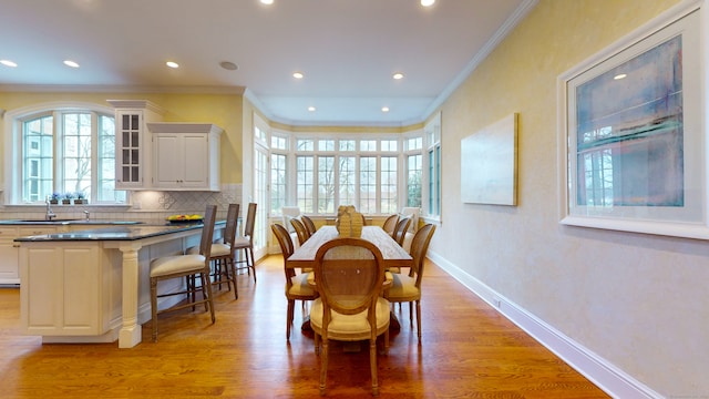 dining space with ornamental molding, sink, and hardwood / wood-style floors