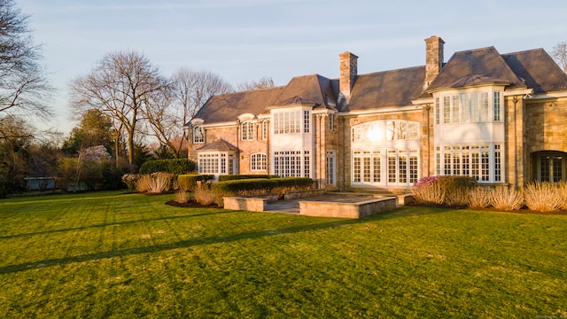 rear view of house featuring french doors and a lawn