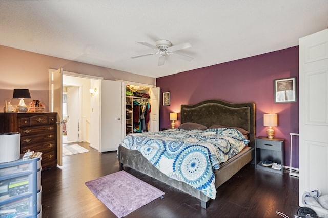 bedroom with a closet, dark hardwood / wood-style flooring, a spacious closet, and ceiling fan