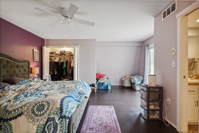 bedroom with a closet, dark hardwood / wood-style flooring, a spacious closet, sink, and ceiling fan