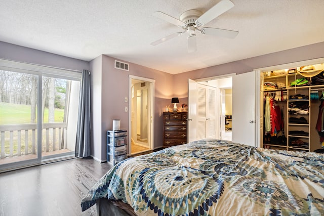 bedroom with access to outside, hardwood / wood-style floors, a walk in closet, ceiling fan, and a textured ceiling