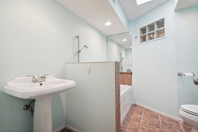 bathroom with toilet, a bathtub, a textured ceiling, a skylight, and tile floors