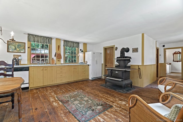 kitchen featuring light brown cabinets, white appliances, dark hardwood / wood-style flooring, a wood stove, and sink