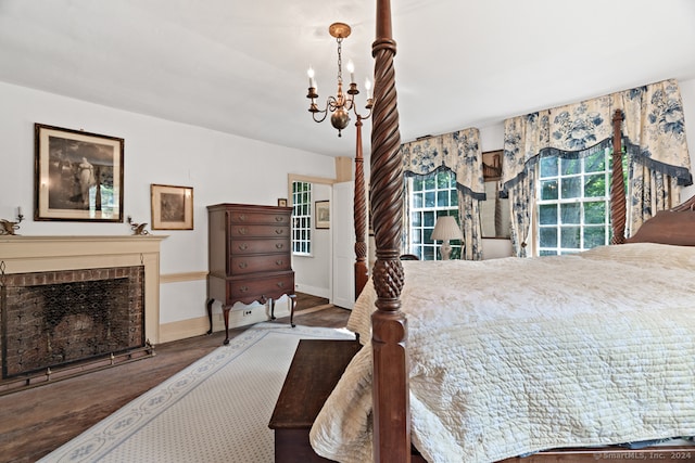 bedroom featuring a notable chandelier, dark wood-type flooring, and a brick fireplace