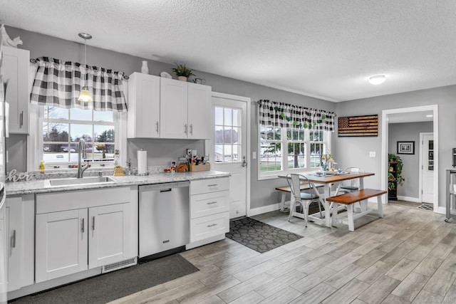 kitchen with a textured ceiling, light hardwood / wood-style floors, stainless steel dishwasher, sink, and white cabinetry