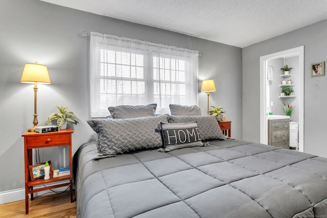 bedroom featuring hardwood / wood-style flooring, ensuite bathroom, and a textured ceiling