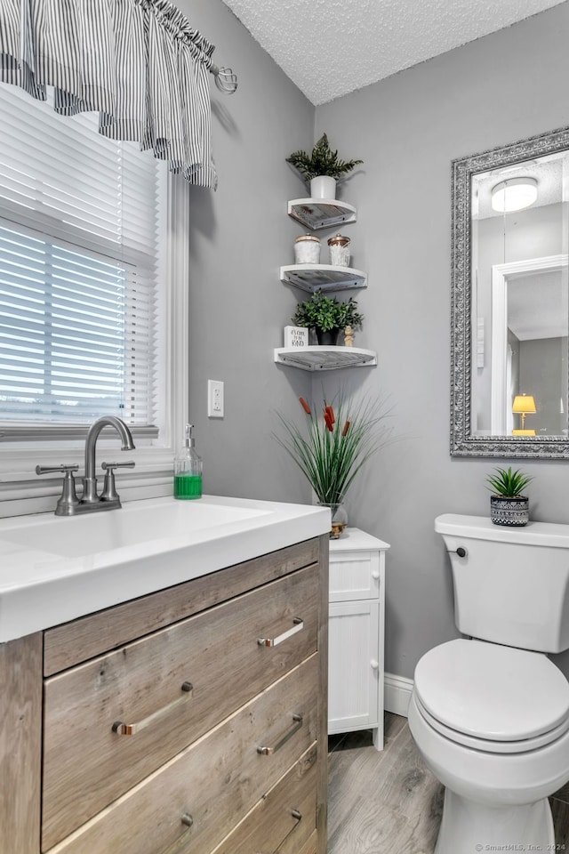 bathroom with vanity, toilet, wood-type flooring, and a textured ceiling