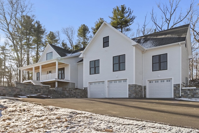 view of front of house with aphalt driveway, covered porch, and an attached garage