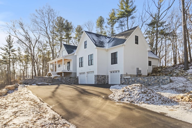 view of snowy exterior with covered porch and a garage