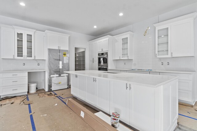 kitchen with a center island, light stone countertops, white cabinetry, and stainless steel appliances