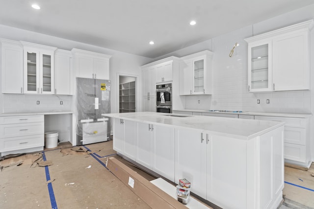 kitchen featuring fridge, a kitchen island, glass insert cabinets, and white cabinets