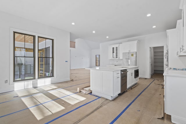 kitchen featuring recessed lighting, a kitchen island, white cabinetry, light countertops, and glass insert cabinets