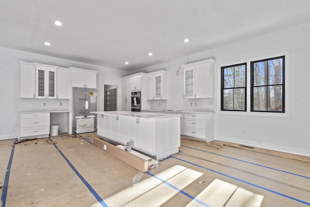 kitchen with light countertops, a kitchen island, glass insert cabinets, and white cabinetry