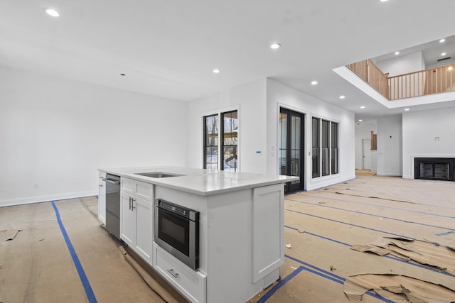 kitchen with black oven, white cabinets, and an island with sink