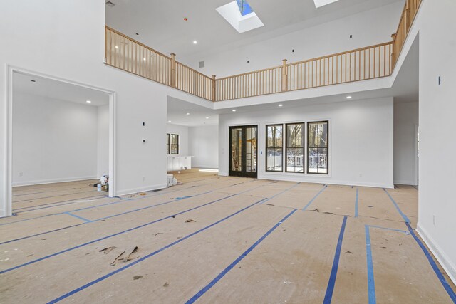 unfurnished living room with a high ceiling and a skylight